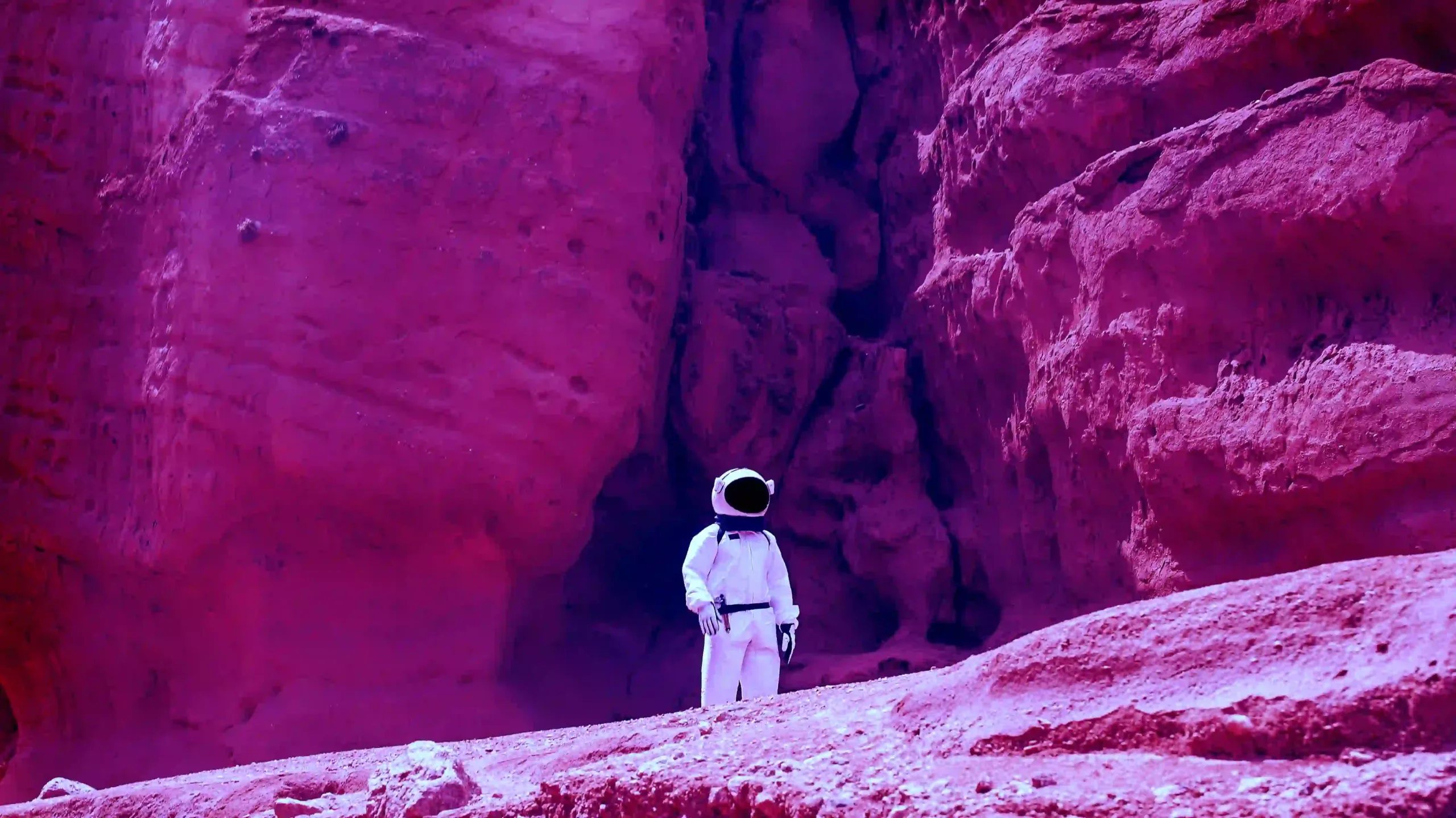 astronaut standing in front of colorful cave